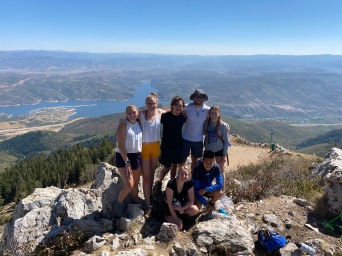 5 people on a rocky outcropping with a distant vista of hills and valley