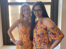 Two girls taking photo while wearing matching yellow dress with flowers on it