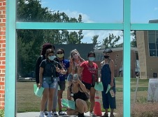 Group selfie captured in a mirrored window on campus