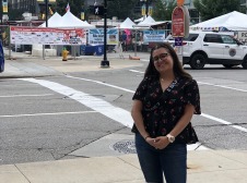 Eva at a cross walk with Heritage Festival tents in the background