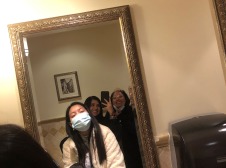 On person takes a picture of her and two friends in a gold framed wall mirror