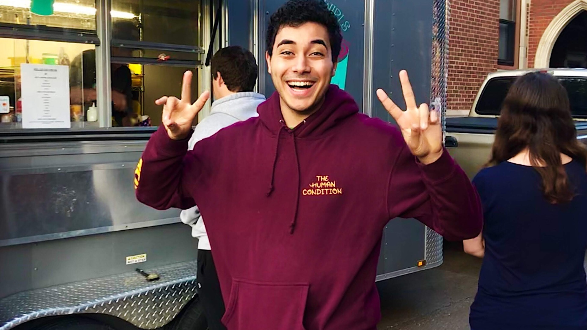 Guy with two peace signs in front of food truck