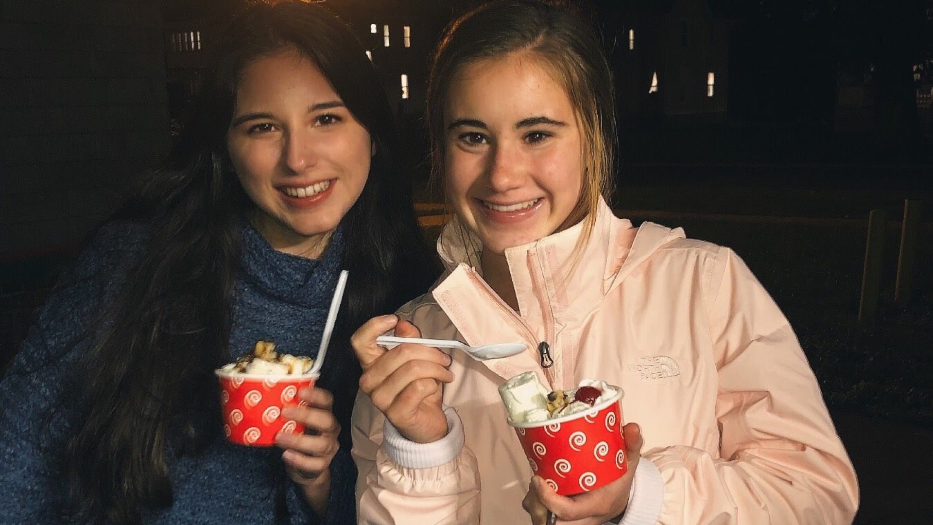 Two girls eating ice cream with street lamp behind them.