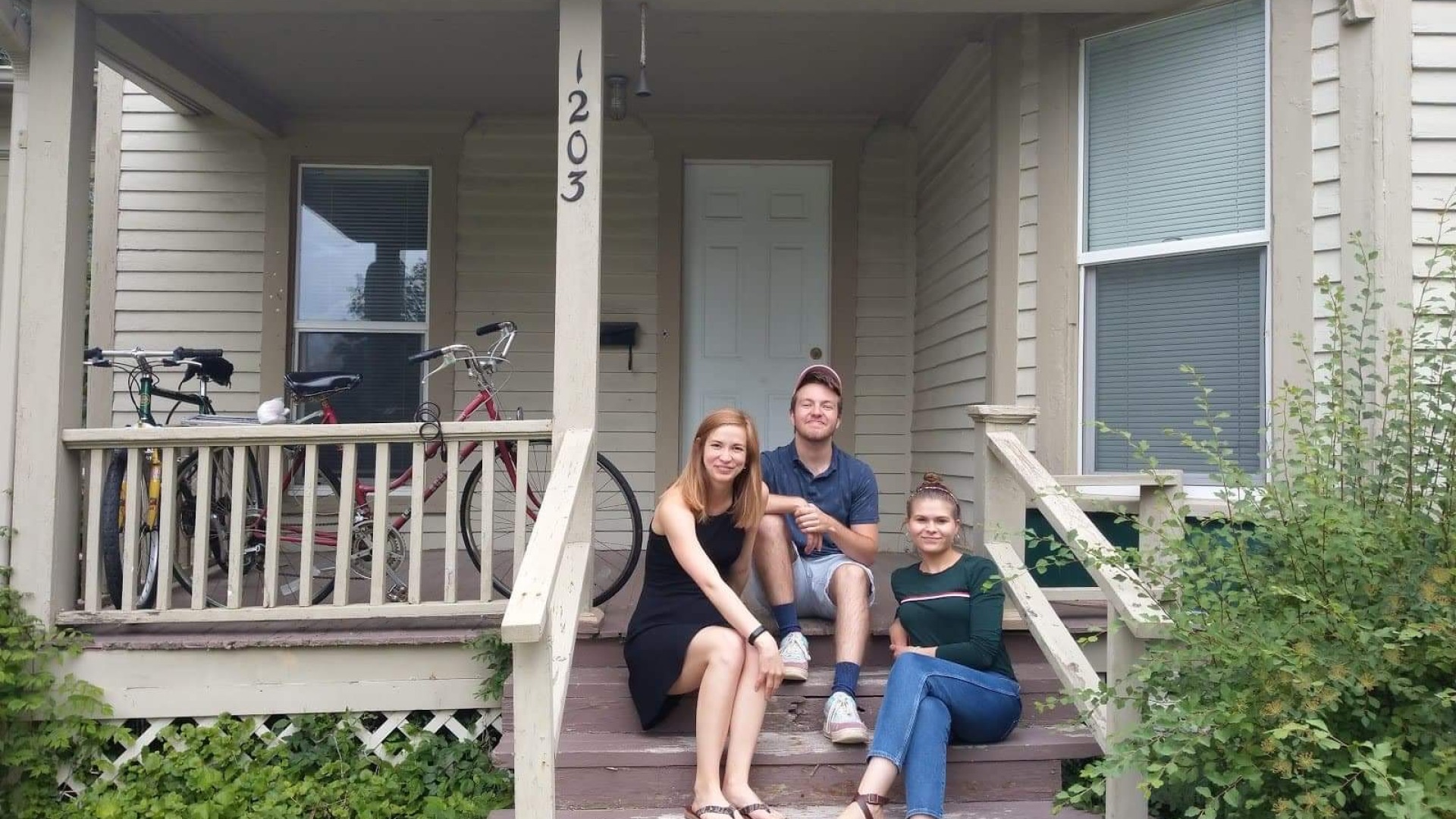 Group of three sitting on front stairs of house