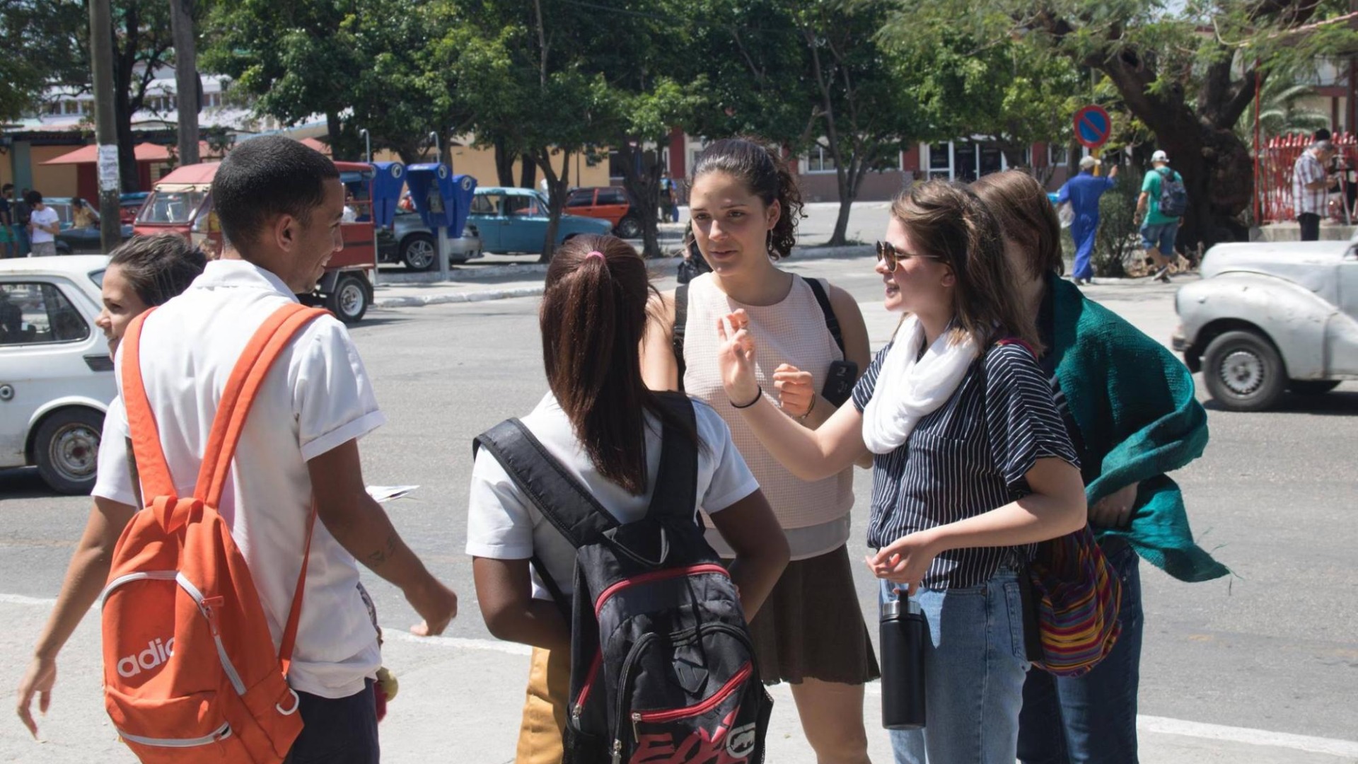 Students with book bags talking on the sidewalk 