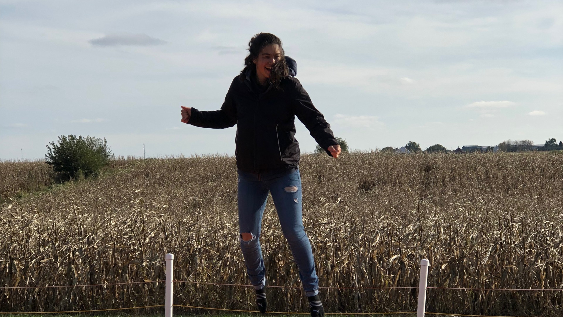 Girl jumping in front of farm field