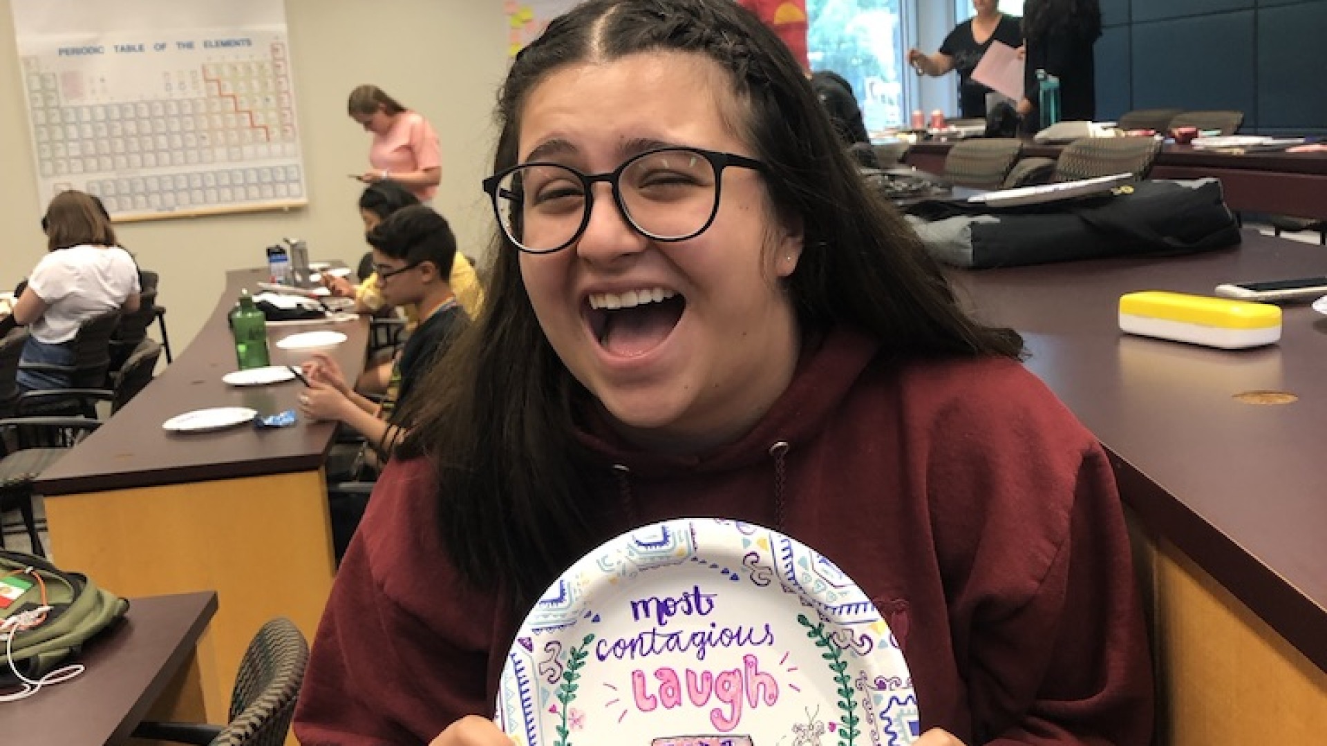 Eva laughing as she displays her award a hand-decorated paper plate with most contagious laugh Eva