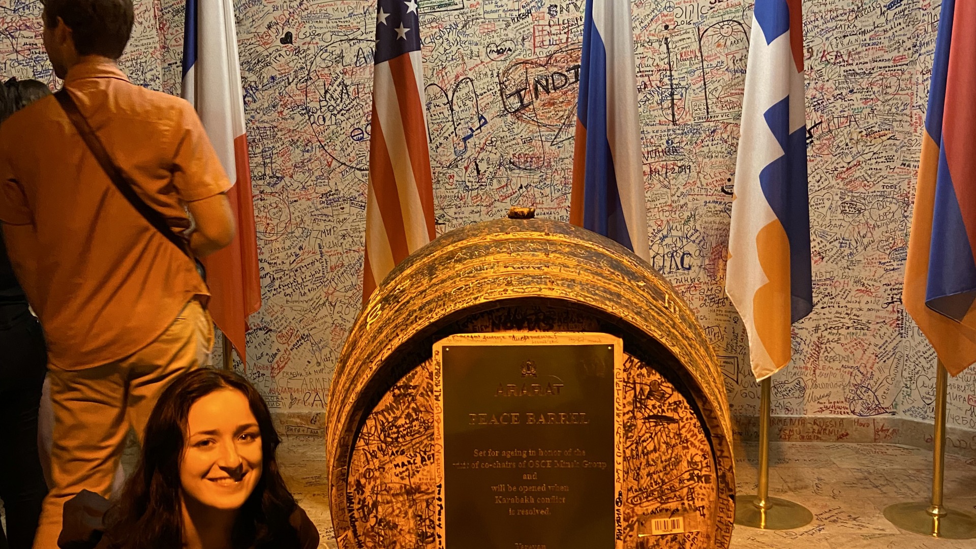 Sophie standing next to a barrel with a plaque reading Peace Barrel and covered in signatures