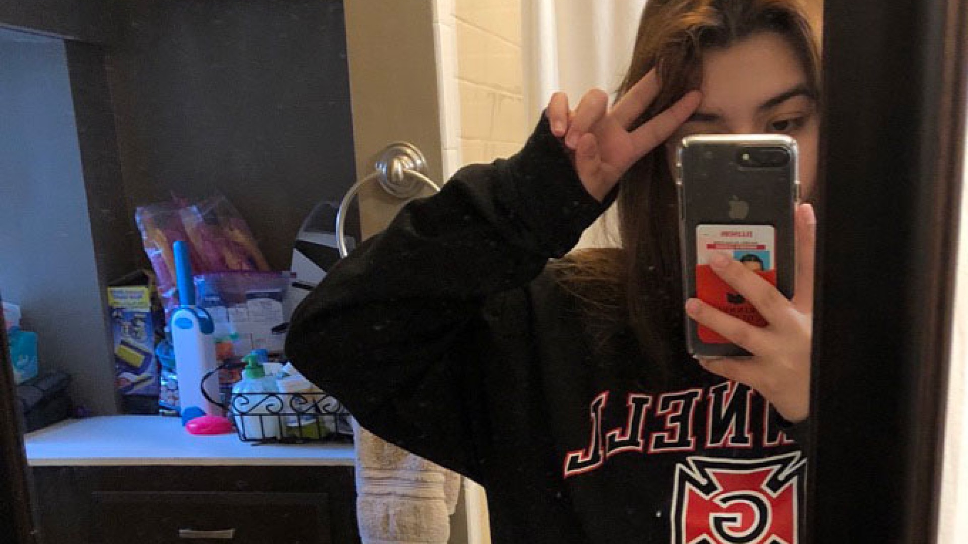 Eva taking a mirror selfie while wearing a black Grinnell College sweatshirt and black shorts 