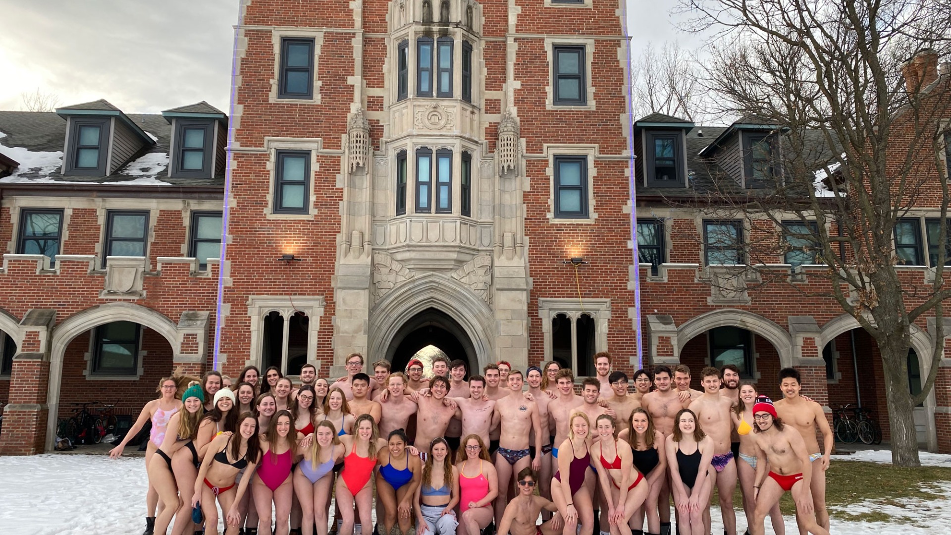 swim team in swimsuits and shoes outside Gates/Rawson with snow on the ground