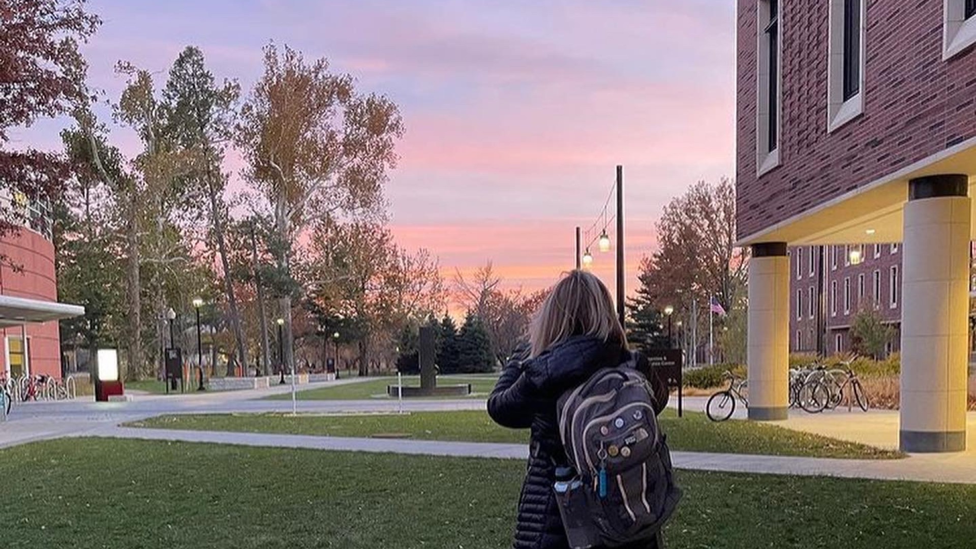 My back faces the camera as I take a picture of the beautiful sunsets in Iowa. I'm near the HSSC, which is one of the new buildings on campus