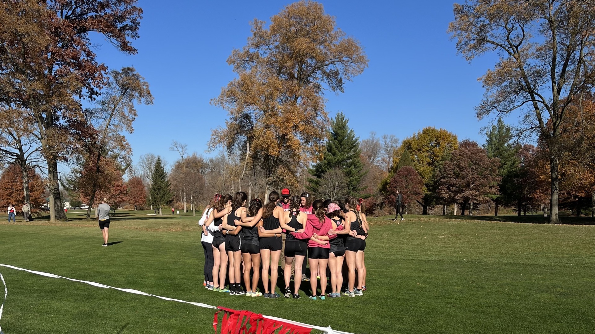 My team (the Bea$ts) huddles together on the grass before an XC meet