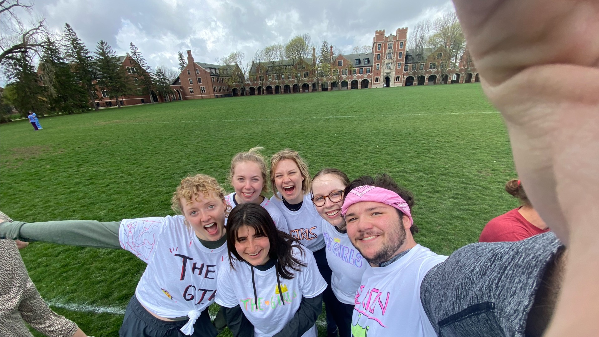 My friends and I huddle together in matching T-shirts for a selfie. You can see the Gates Tower (a residential hall building) in the background