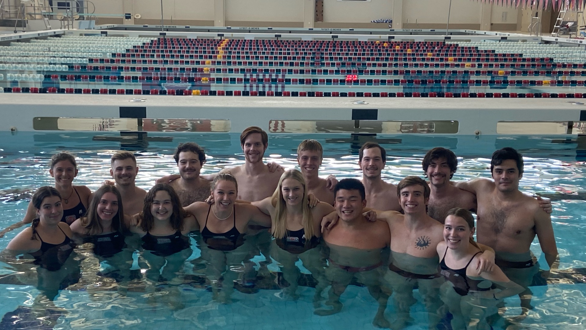 Swim team smiling at the camera inside the pool