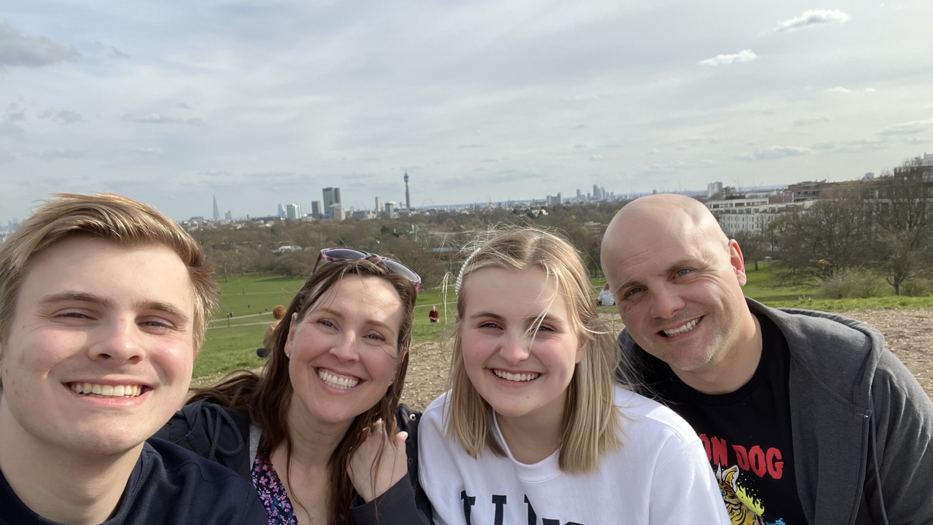 My family and I smiling at Primrose Hill with lots of greenery in the background
