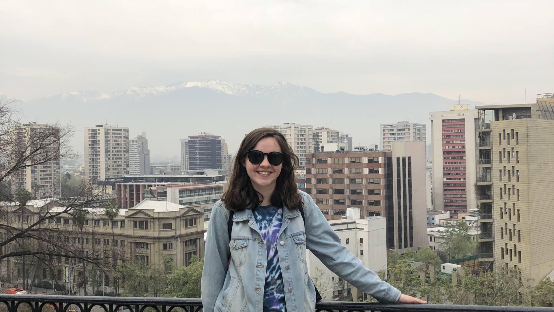 Me leaning against a fence with Chilean skyscrapers in the foggy background!