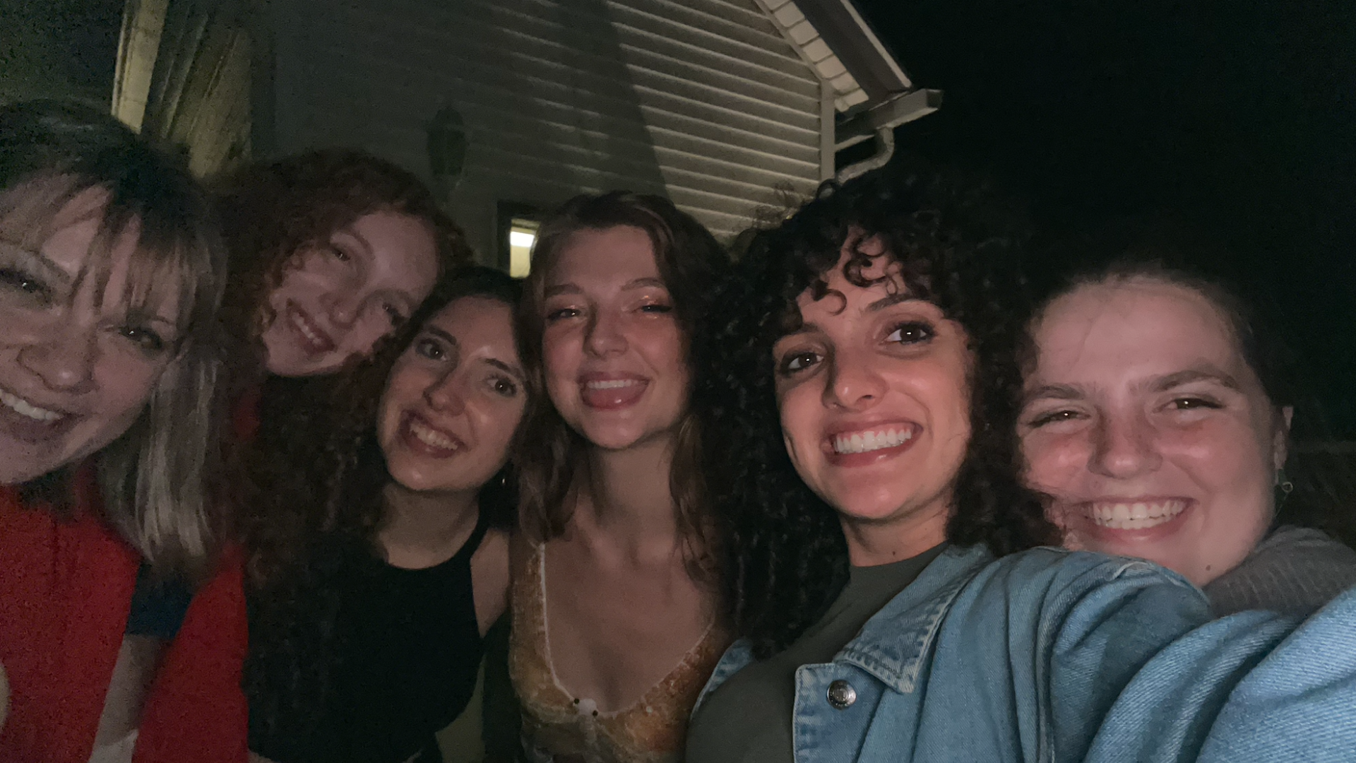 My five friends and I take a wide selfie shot of us together at nighttime. We're outside of an off-campus house!