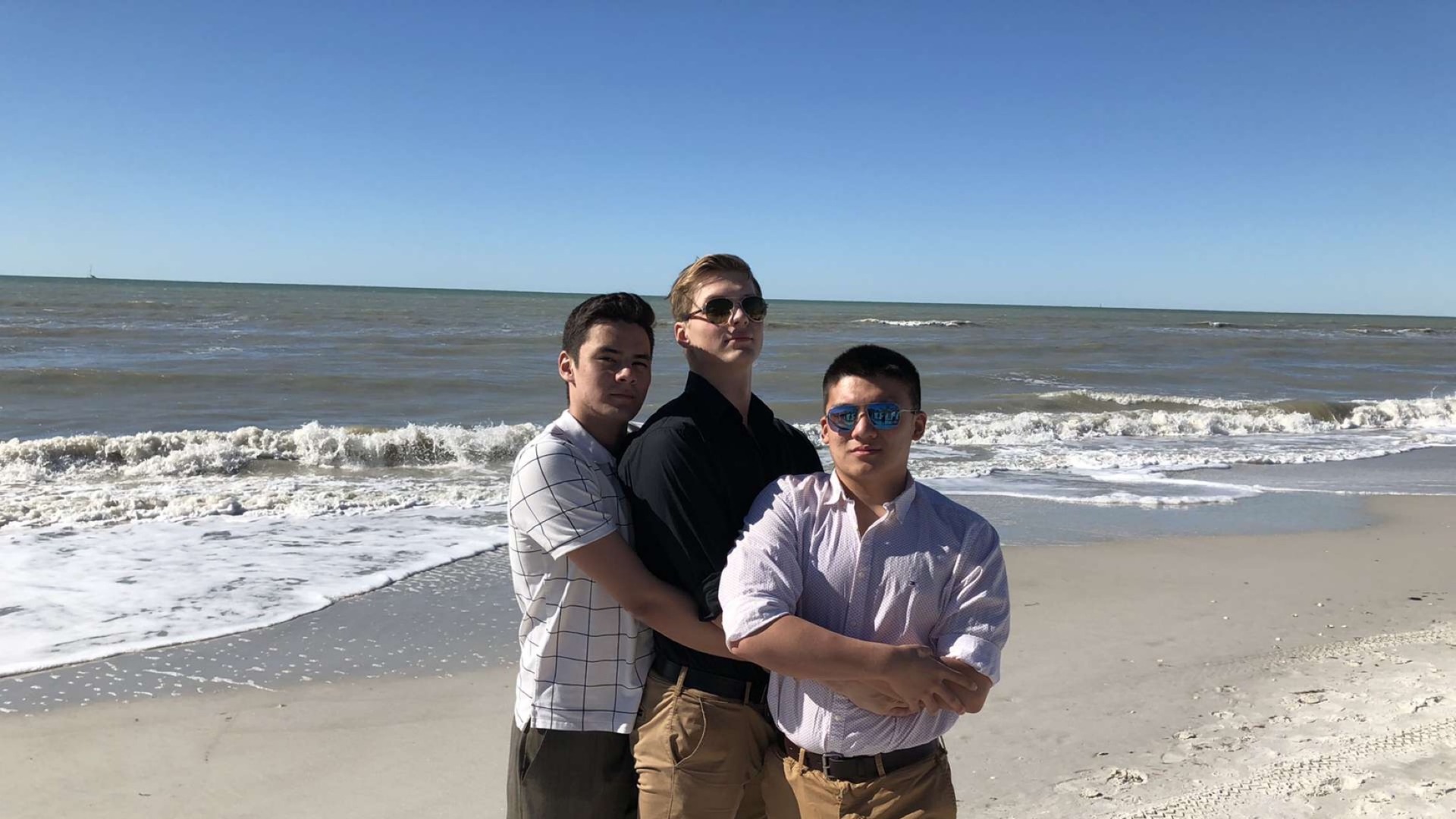 Me and my three friends all hug together in front of the beach