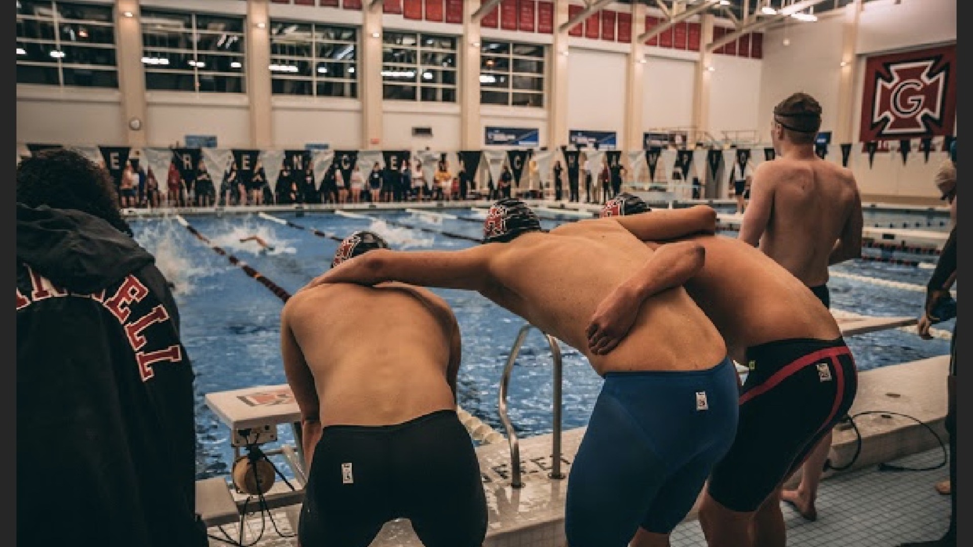 Three swimmers with their caps on ready themselves and focus at the pool.