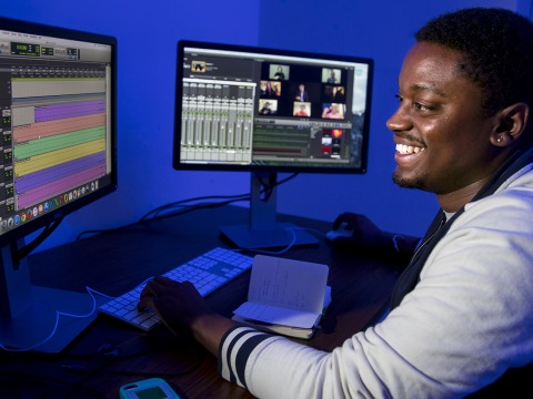 Student in front of two monitors displaying parts of the editing process