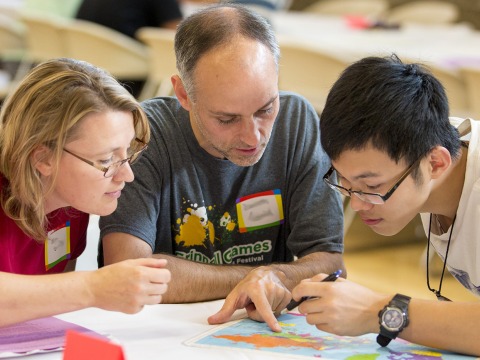 Hosts and student peer over a map together