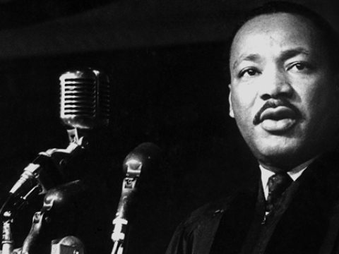 Black and white photo of Dr. King behind a bank of mics