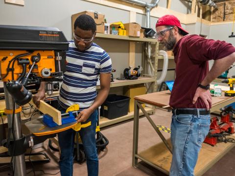 Monty Roper supervises a student with machinery at the maker lab