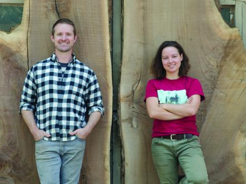 Tor Erickson ’01 and Isabella Kugel ’20 stand in front of wood slabs that were made into a desk that now greets visitors in the new Admission and Student Financial Services center.  