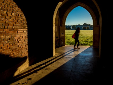 Student passing arches in Gates Rawson Tower