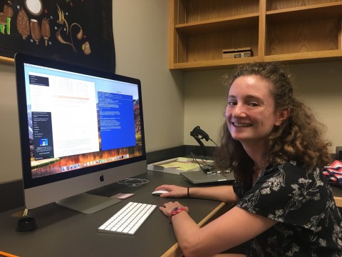 Lauren Frankel in front of computer monitor looking at camera.