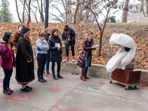 Students and Professor Lee Running critique a sculpture in an outdoor space