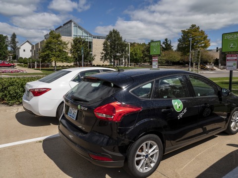 Two zipcars parked in lot across from Chrystal Center