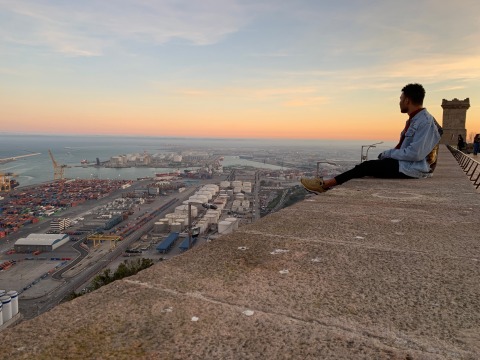 Max Hill sitting on a wall at Castle Montjuic, Barcelona, Spain, at sundown