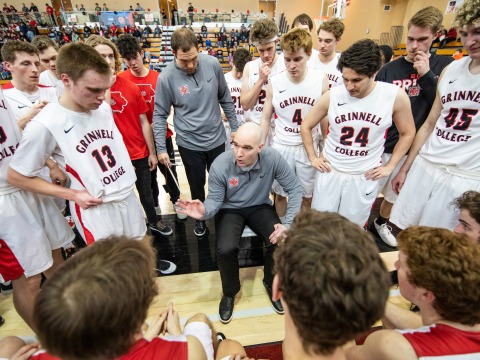 Head coach David Arseneault Jr. talks with the men's basketball team during a timeout.