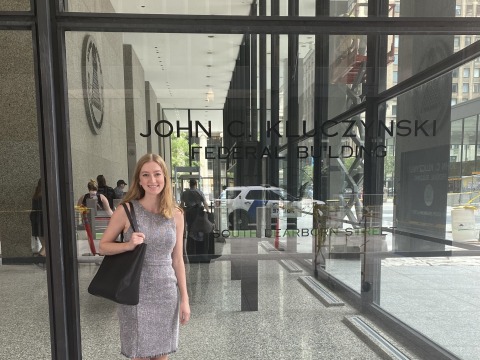 Claire standing in front of building window 