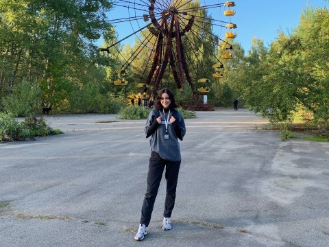 Sophie in Chernobyl with defunct Ferris wheel in the background