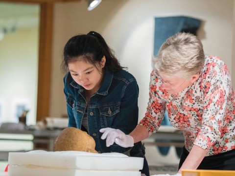 A professor and student examine a marble Roman portrait head, believed to be from 1st century, in the print study room of the Burling Library