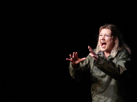 Lucy screams with anguish in front of a dark background for theater