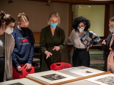 Professor Jenny Anger and a group of students examine an artwork in the Print and Drawing Study Room