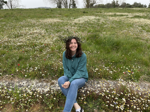 Elisabeth Kille sitting near the flowers and grass at the site of the Ancient Olympic Games