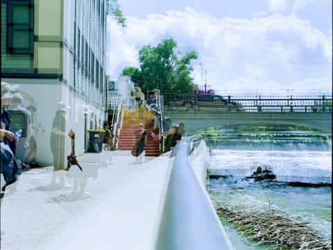 A saturated image of an outdoors scene. There isa bridge and a staircase. You can see transparent images on people throughout the image.
