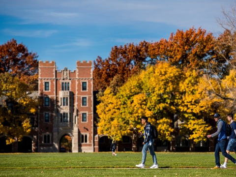 students walking on campus in front of gates