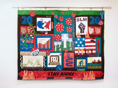 A colorful quilt hangs on the wall