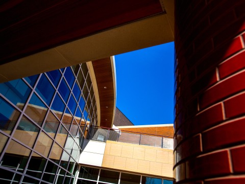 An abstract angle of the Joe Rosenfield Center. On the left, a glass, gridded wall and on the right, a close up of a red bricked pillar.