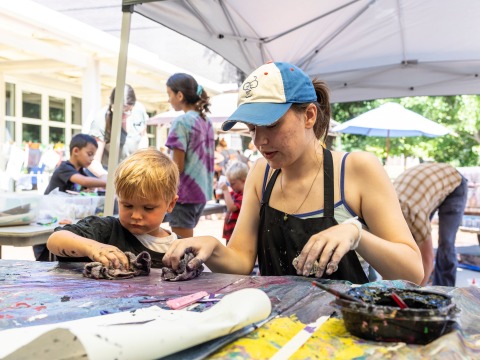 student working on an art project with small child outside