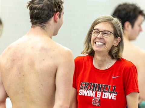 Coach Erin Hurley smiling while listening to a swimmer after his race.