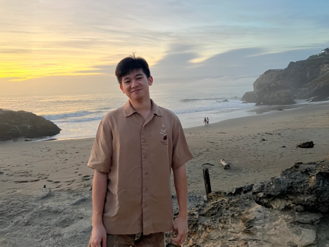 Nam Do on a beach with a beautiful sunset behind him