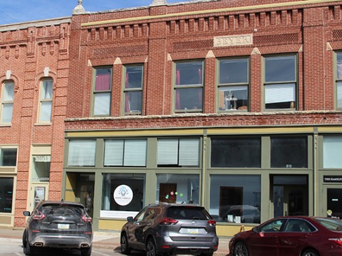 A brick and stone facade with Beyers carved on a plaque over the 2nd story windows houses a few businesses behind large windows on the first