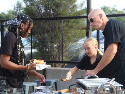 A business owner serves pizza to a Grinnell College student