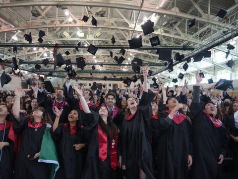 Graduates of the class of 2025 throw their caps in the air at commencement